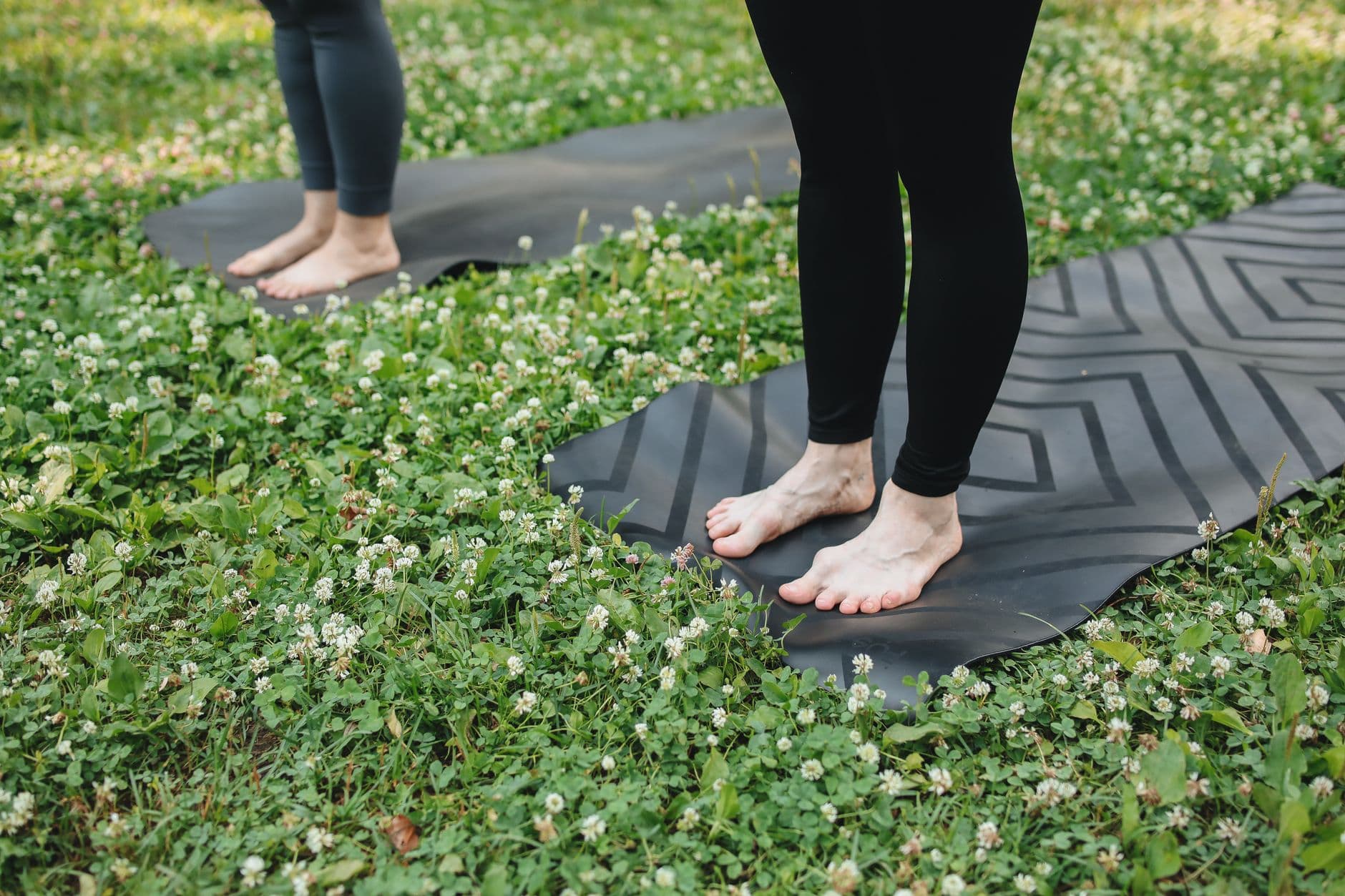 Femme pratiquant la posture de la montagne Tadasana pieds nus sur herbe, exercice d'ancrage chakra racine