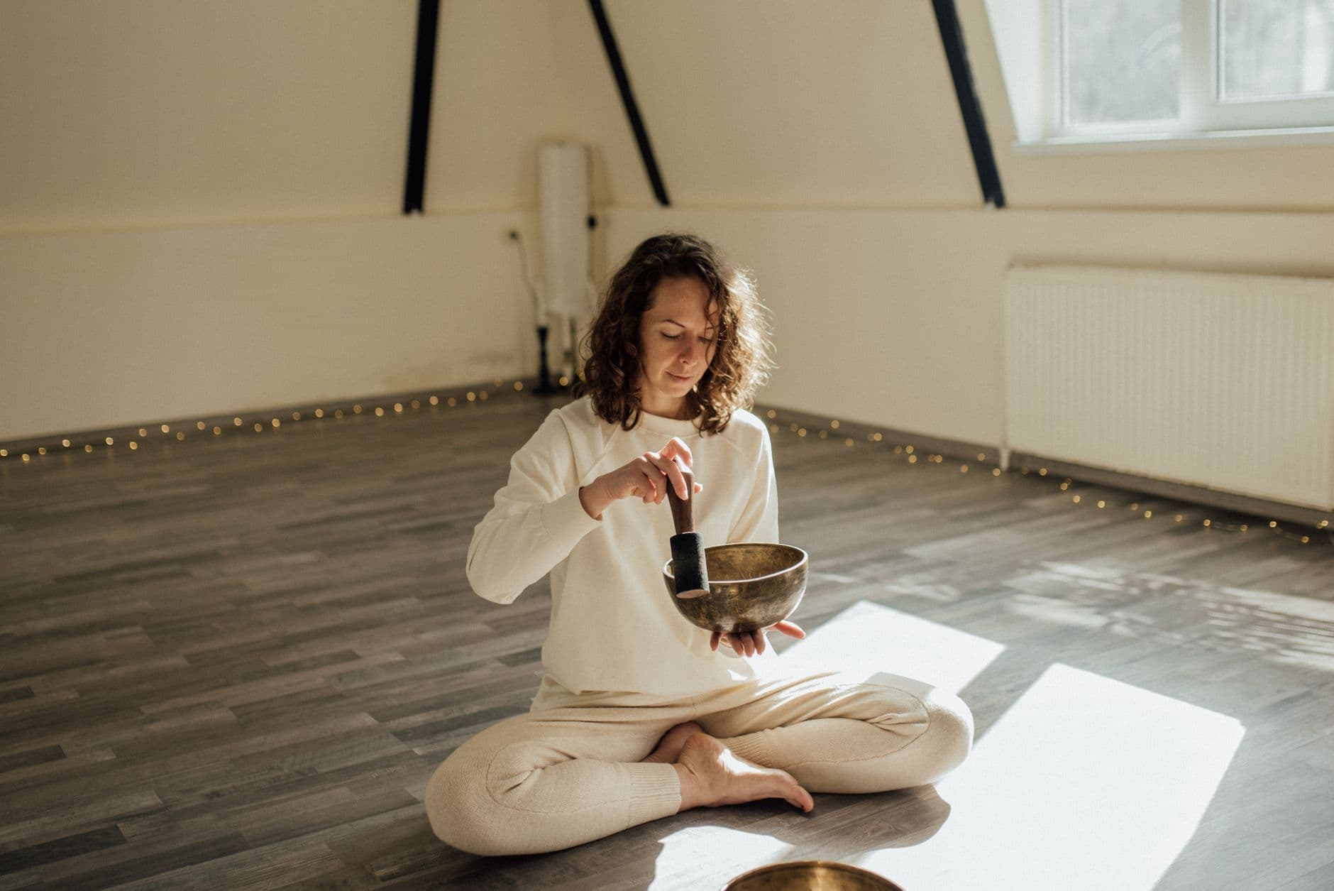 Femme assise en silence, mains posées sur les genoux, lumière naturelle matinale douce